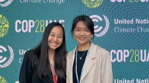 Two women smiling and standing in front of a backdrop that reads United Nations Climate Conference COP28UAE