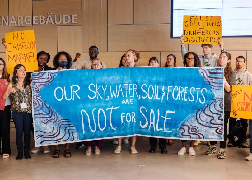 A group of young activists holding a banner that reads our sky, water, soil, forests are not for sale